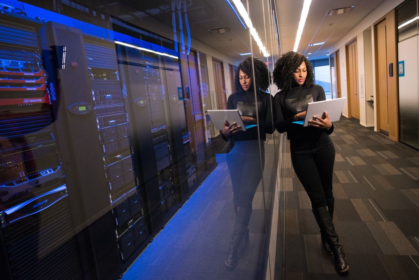 An engineer holding a laptop beside a rack of servers